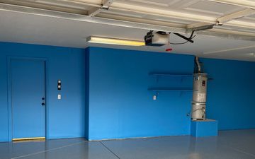 An empty garage with blue walls and a water heater.