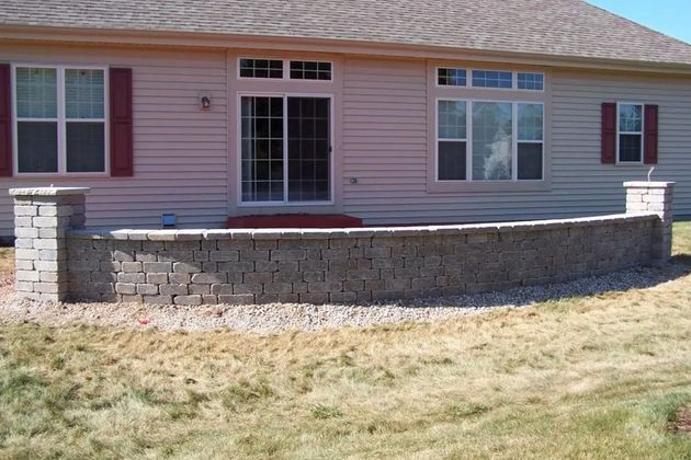Single-story house with pink siding and a low stone retaining wall in the front yard