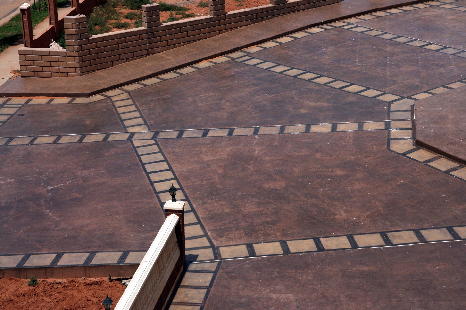 Paved courtyard with brick borders and a low white fence in the foreground