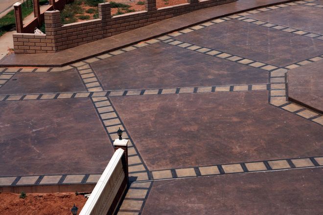 Paved courtyard with brick borders and a low white fence in the foreground