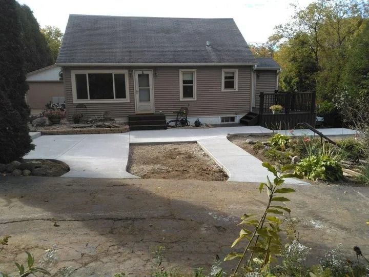 Front yard with a house, fresh concrete walkway, and a patch of bare ground in the center