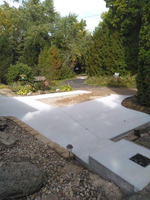 Concrete patio and gravel path in a landscaped garden with trees and shrubs