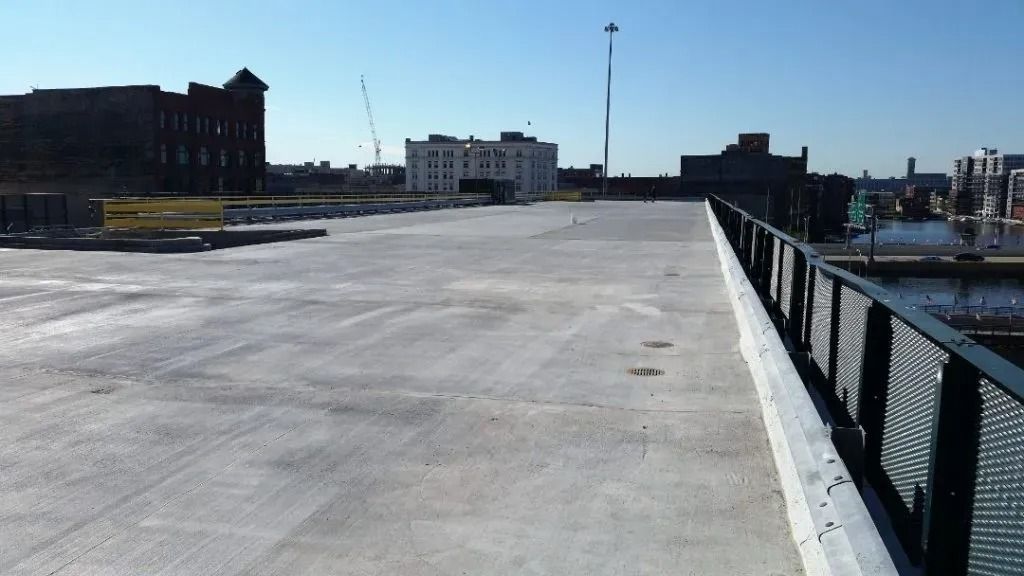 Empty waterfront promenade with metal railing and buildings under a clear blue sky