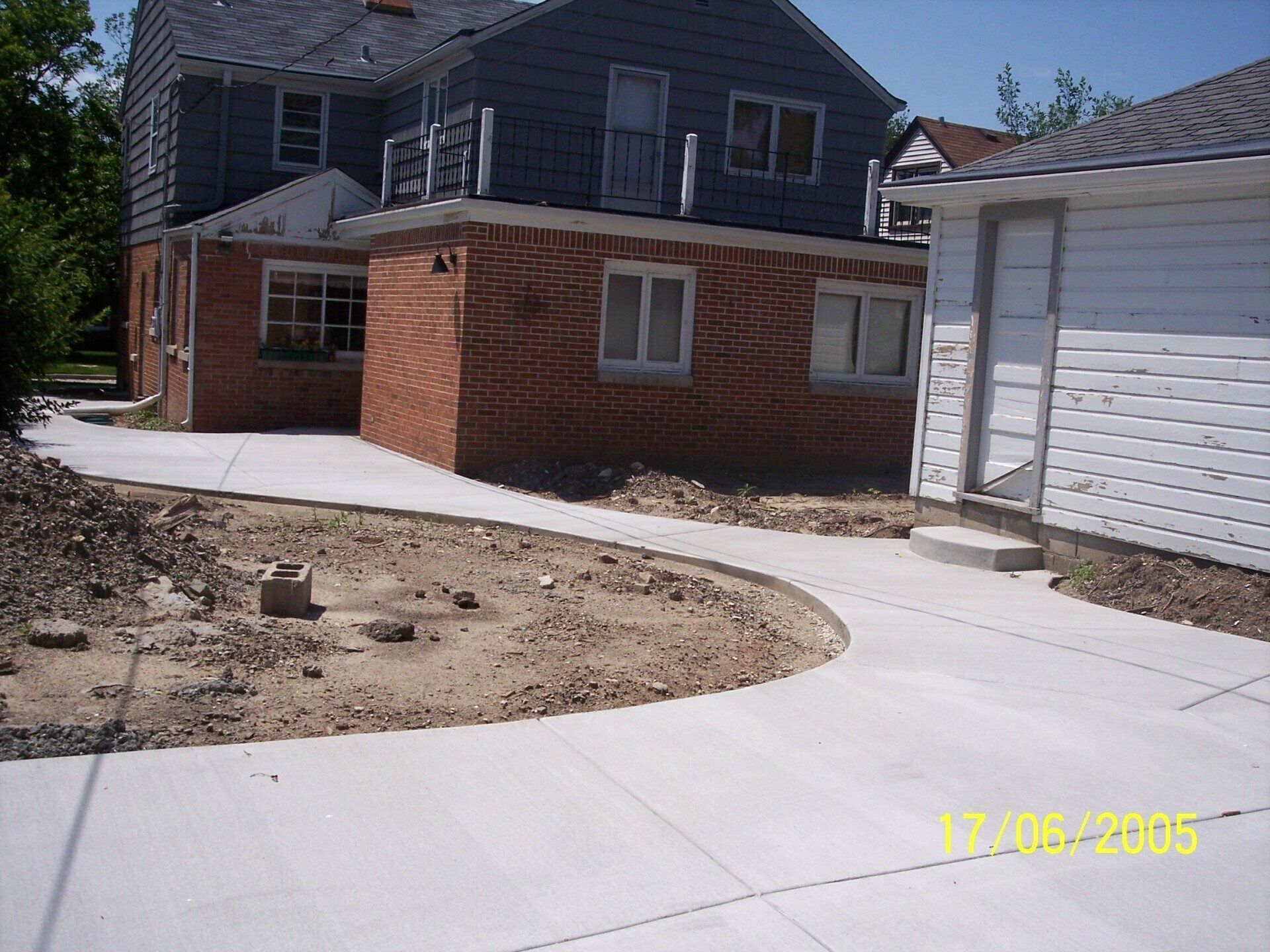 Brick house with a curved concrete driveway beside a white garage in winter.