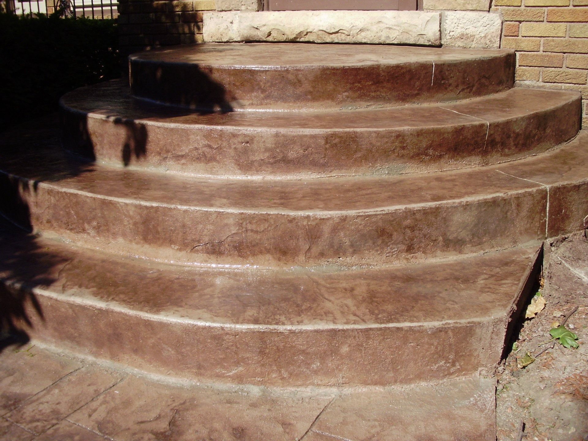 Curved, brown-stained concrete steps leading up to a residential entrance.