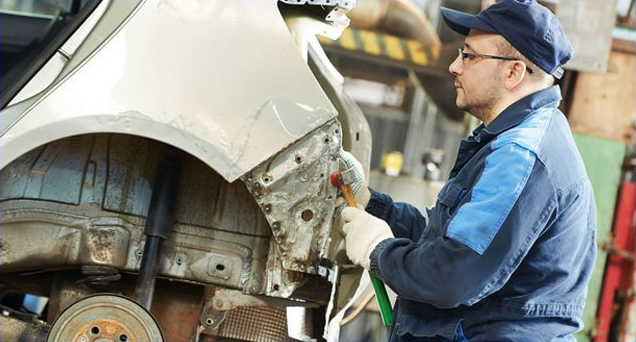 Mechanic straightening car frame