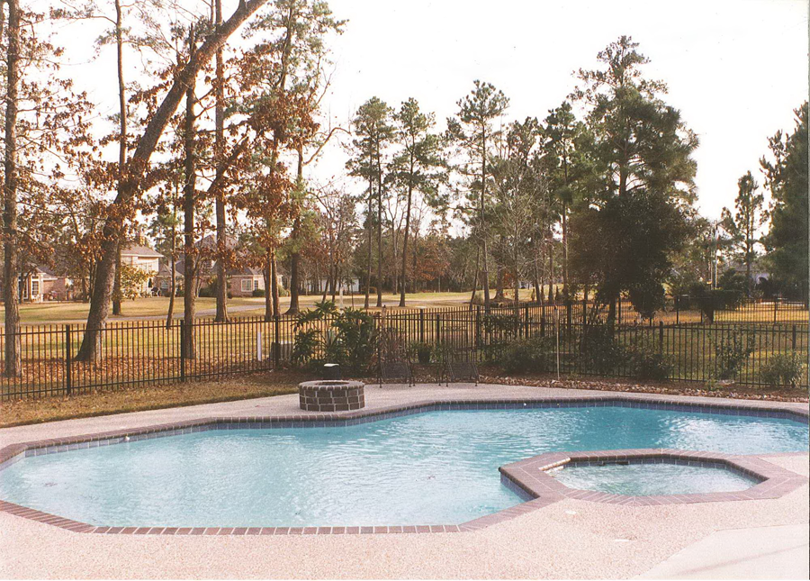 a large swimming pool surrounded by trees and a fence