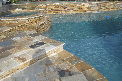 a swimming pool with a stone border and steps leading to it .