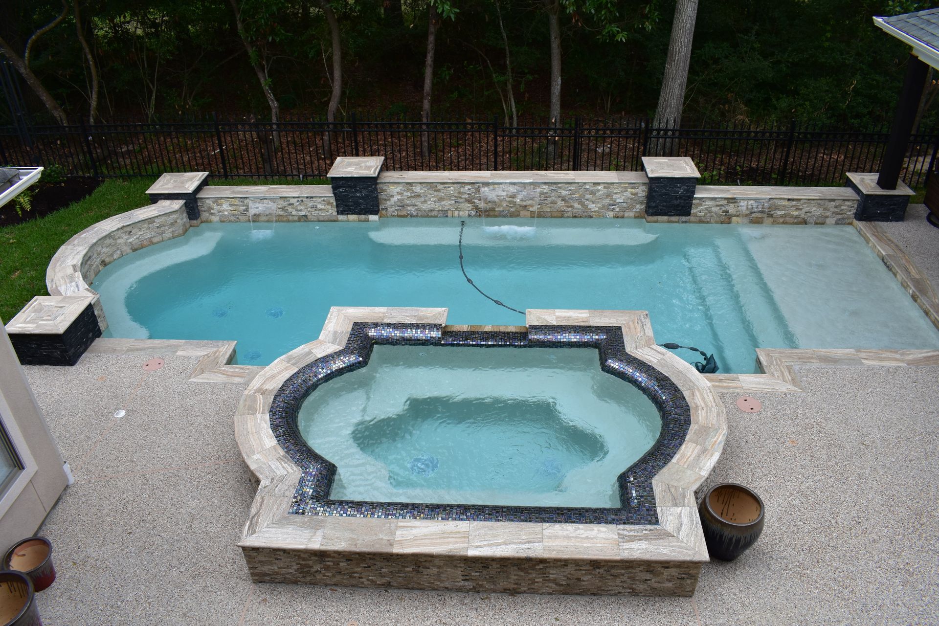 A swimming pool and spa surrounded by a stone patio.