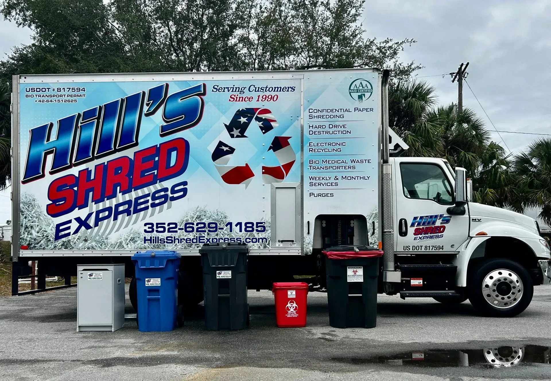 Hill's Shred Express truck with various colored recycling bins. Text and logo on the side of the truck.