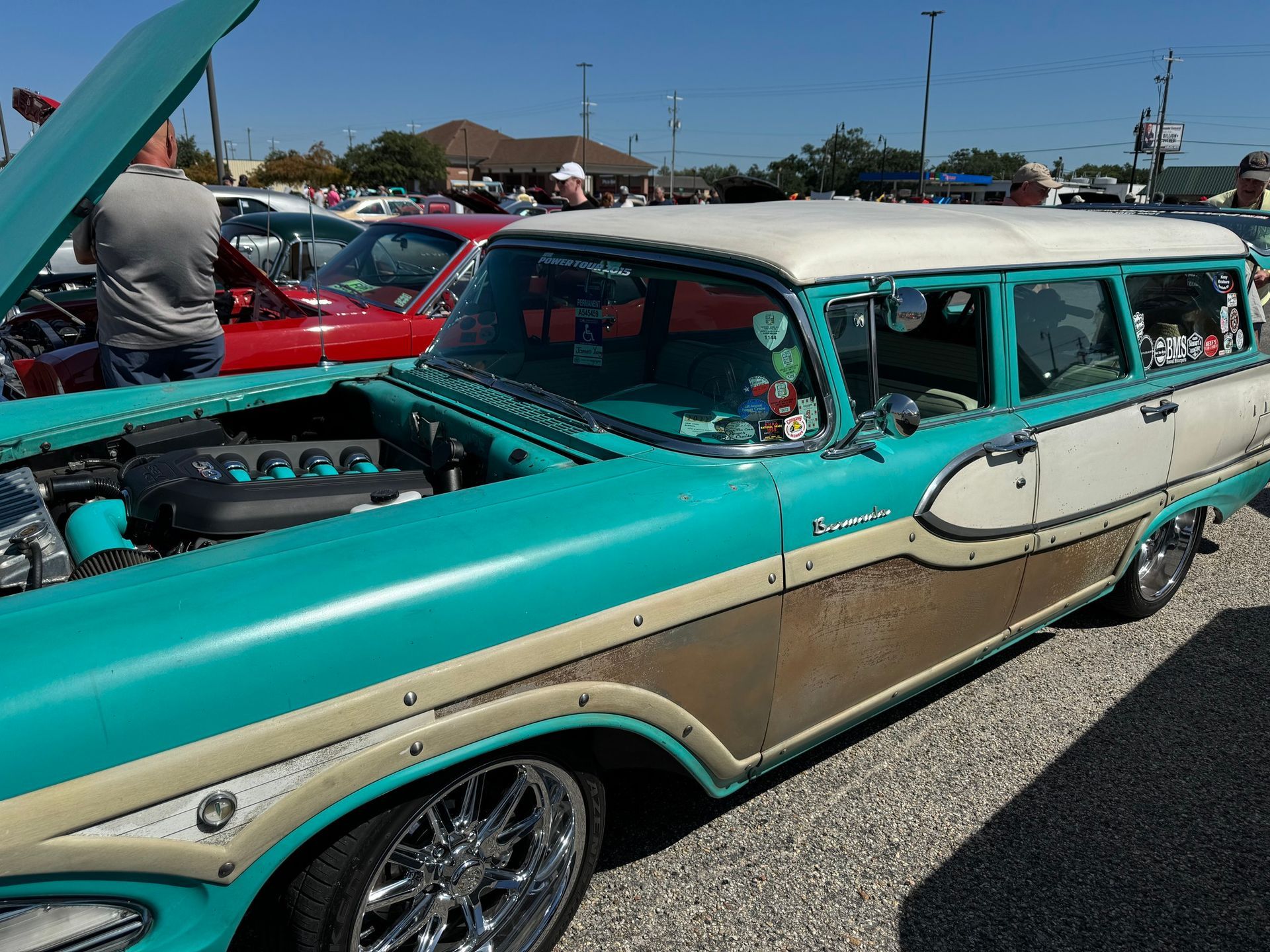 A blue and white car with the hood up is parked in a parking lot
