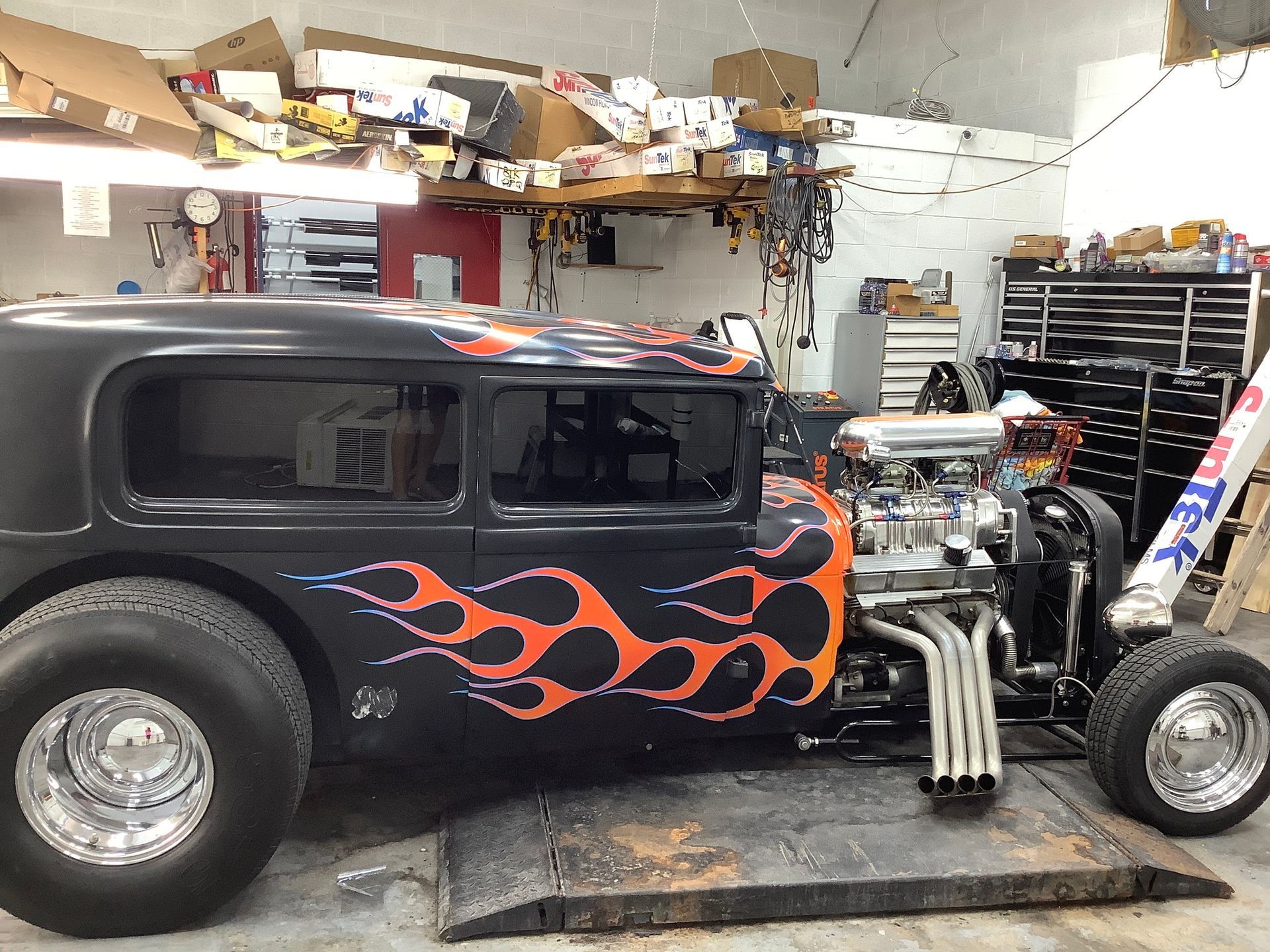 A black car with flames painted on the side is parked in a garage