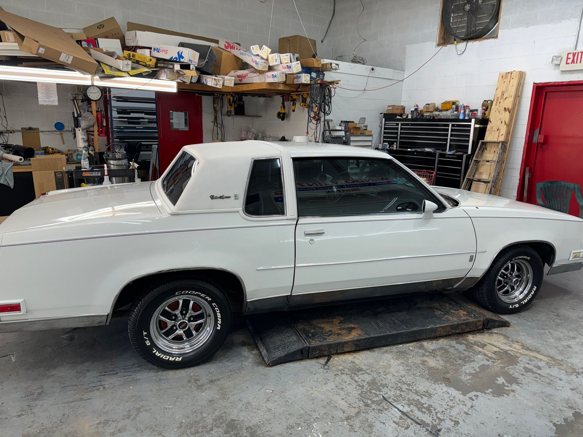 A white car is parked on a lift in a garage.