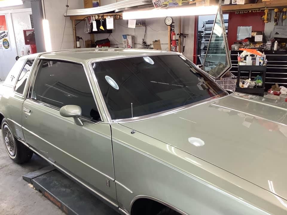 A silver car is parked on a lift in a garage.