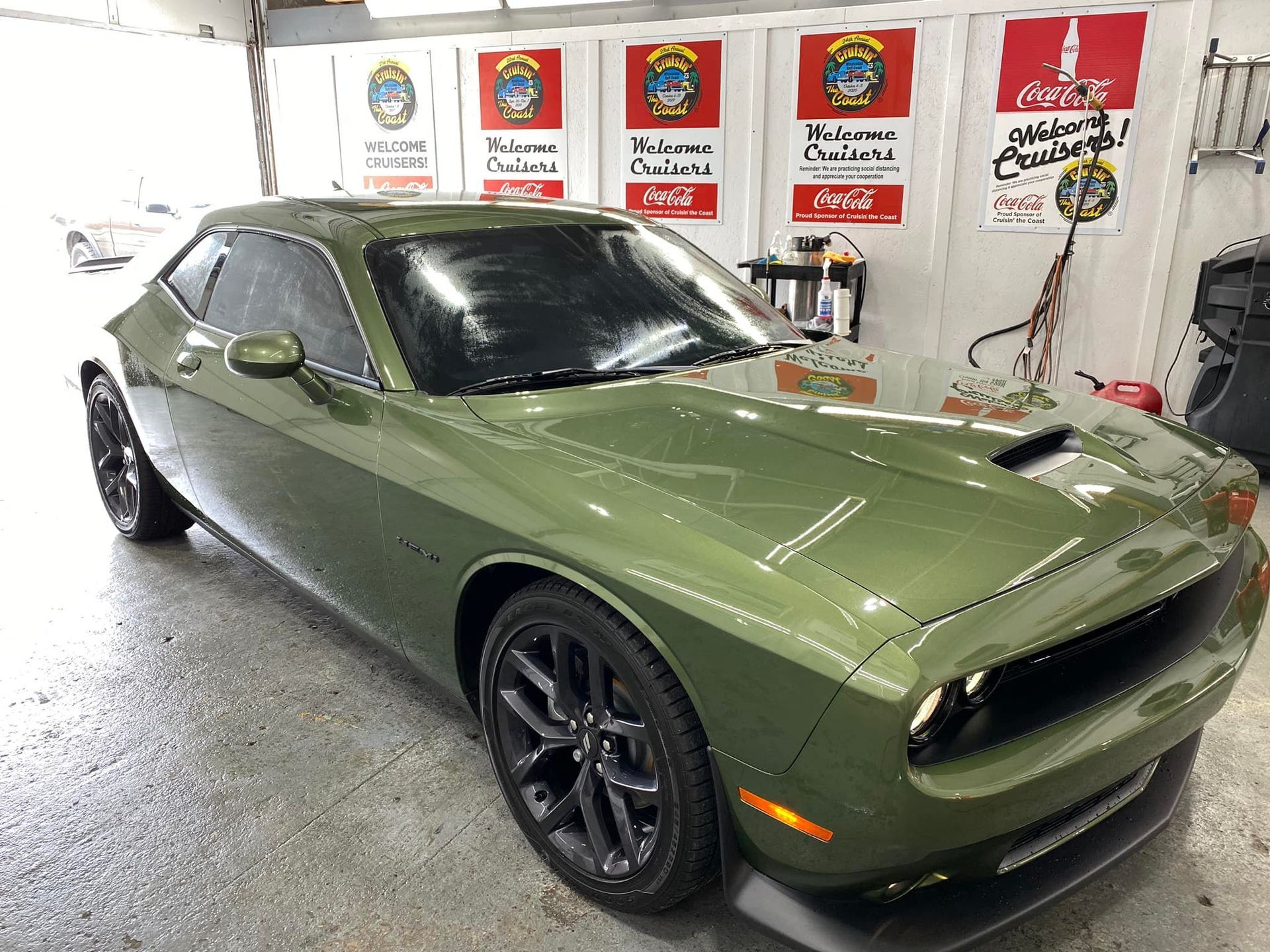 A green dodge challenger is parked in a garage.