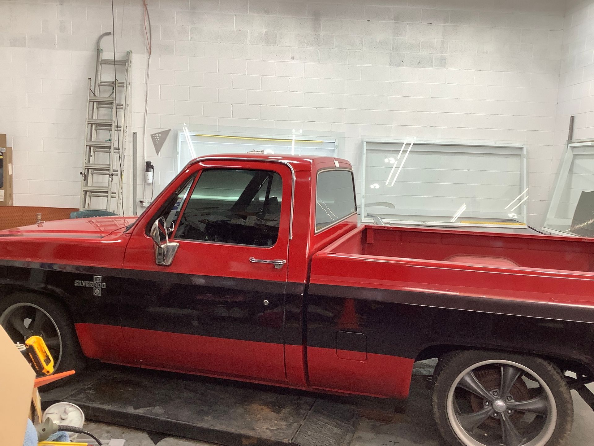 A red and black truck is parked in a garage.
