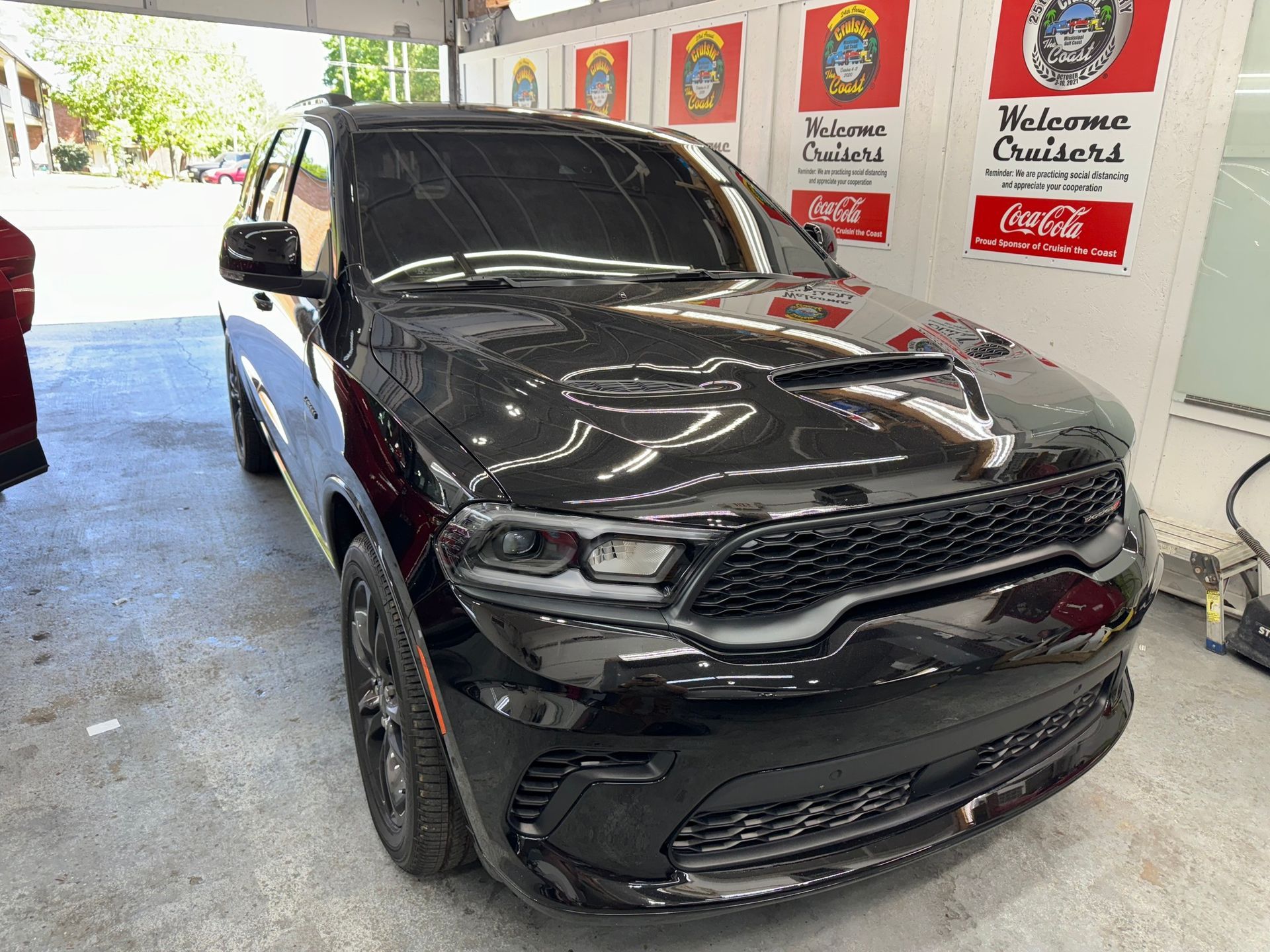 A black dodge durango is parked in a garage next to a coca cola sign.