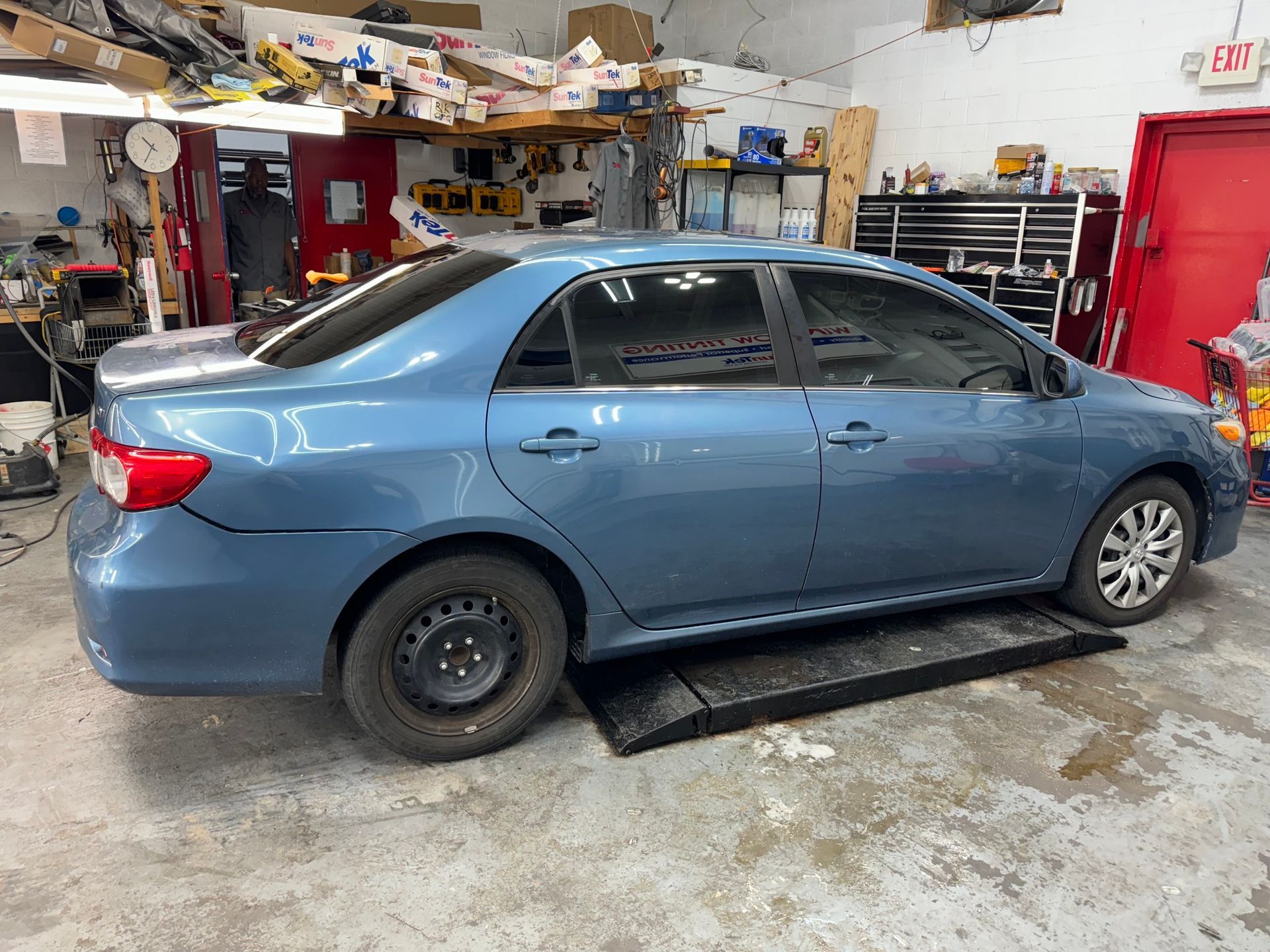 A blue car is parked on a ramp in a garage.