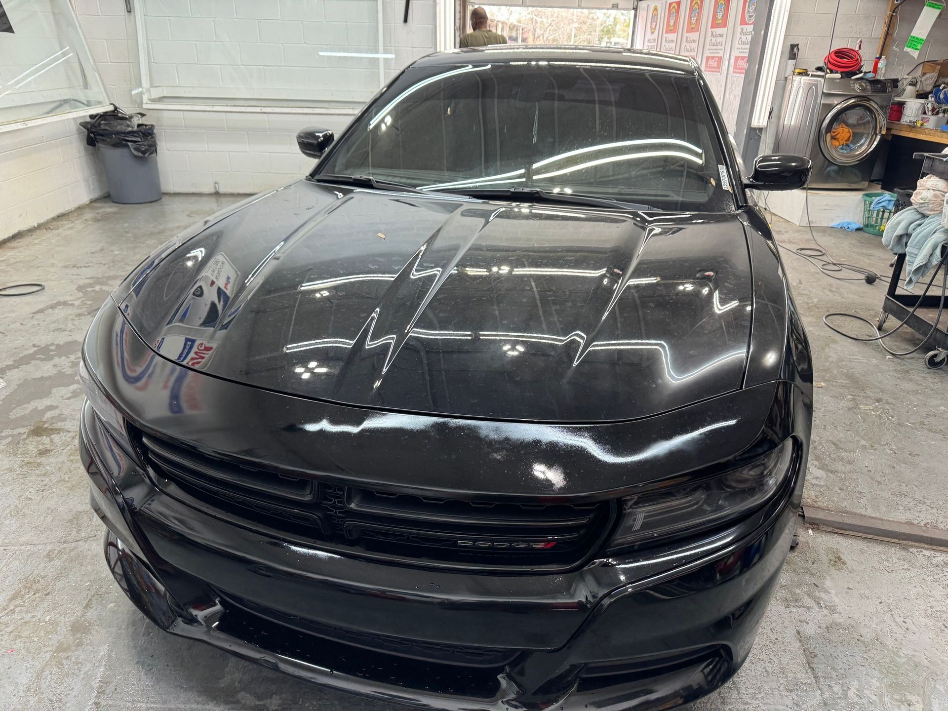 A black dodge charger is parked in a garage.