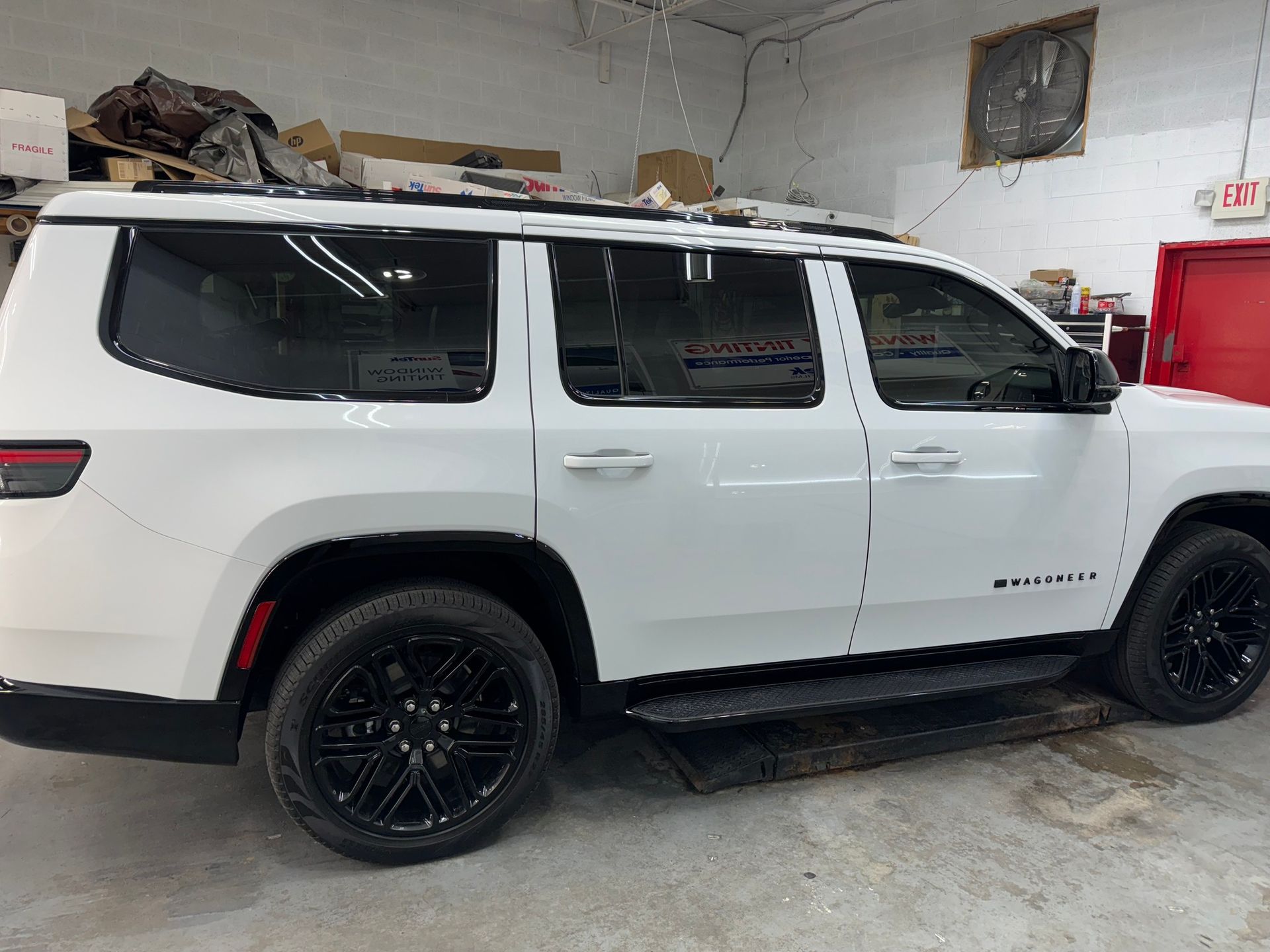 A white jeep wrangler is parked in a garage.