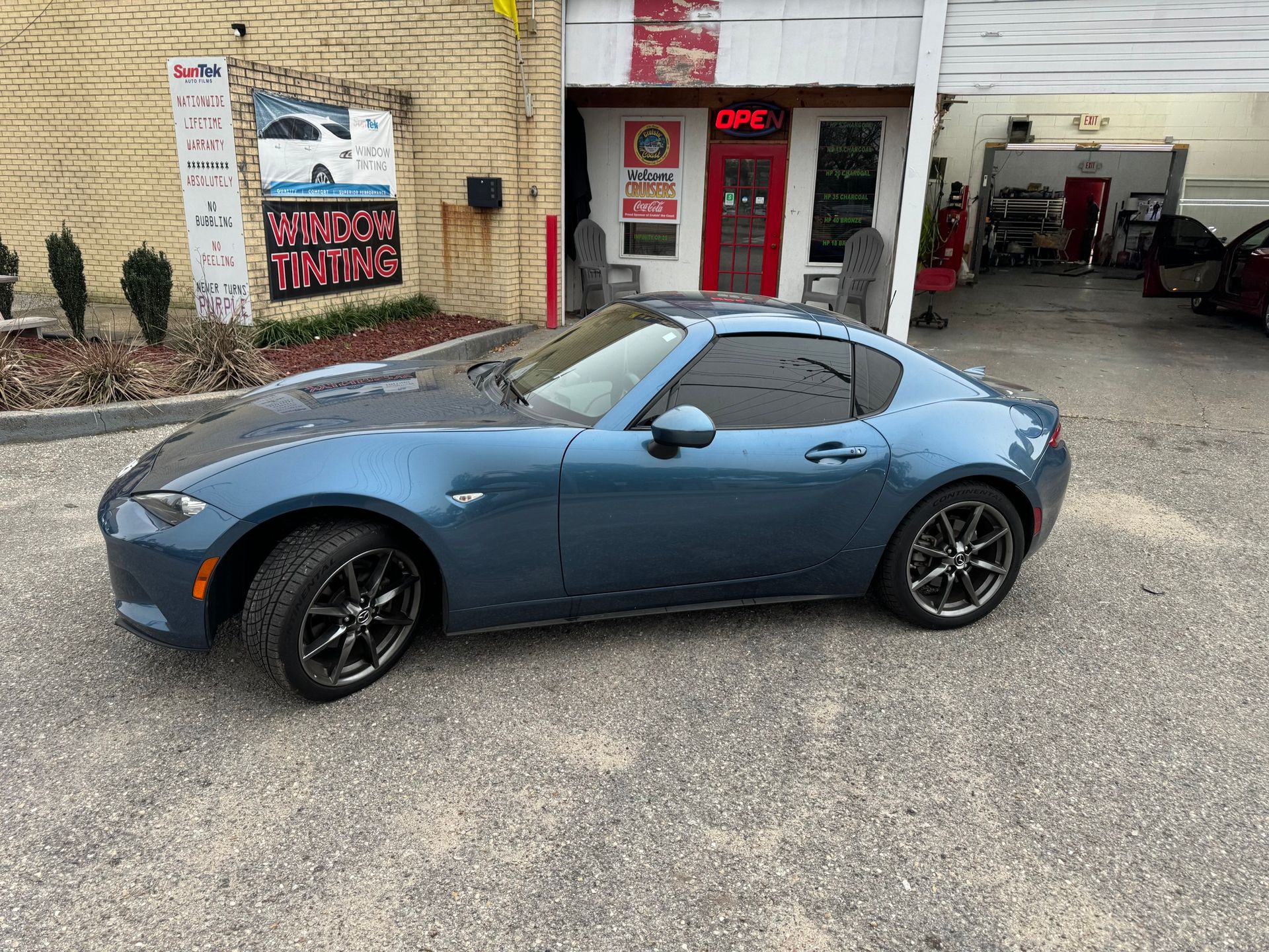 A blue sports car is parked in front of a building.