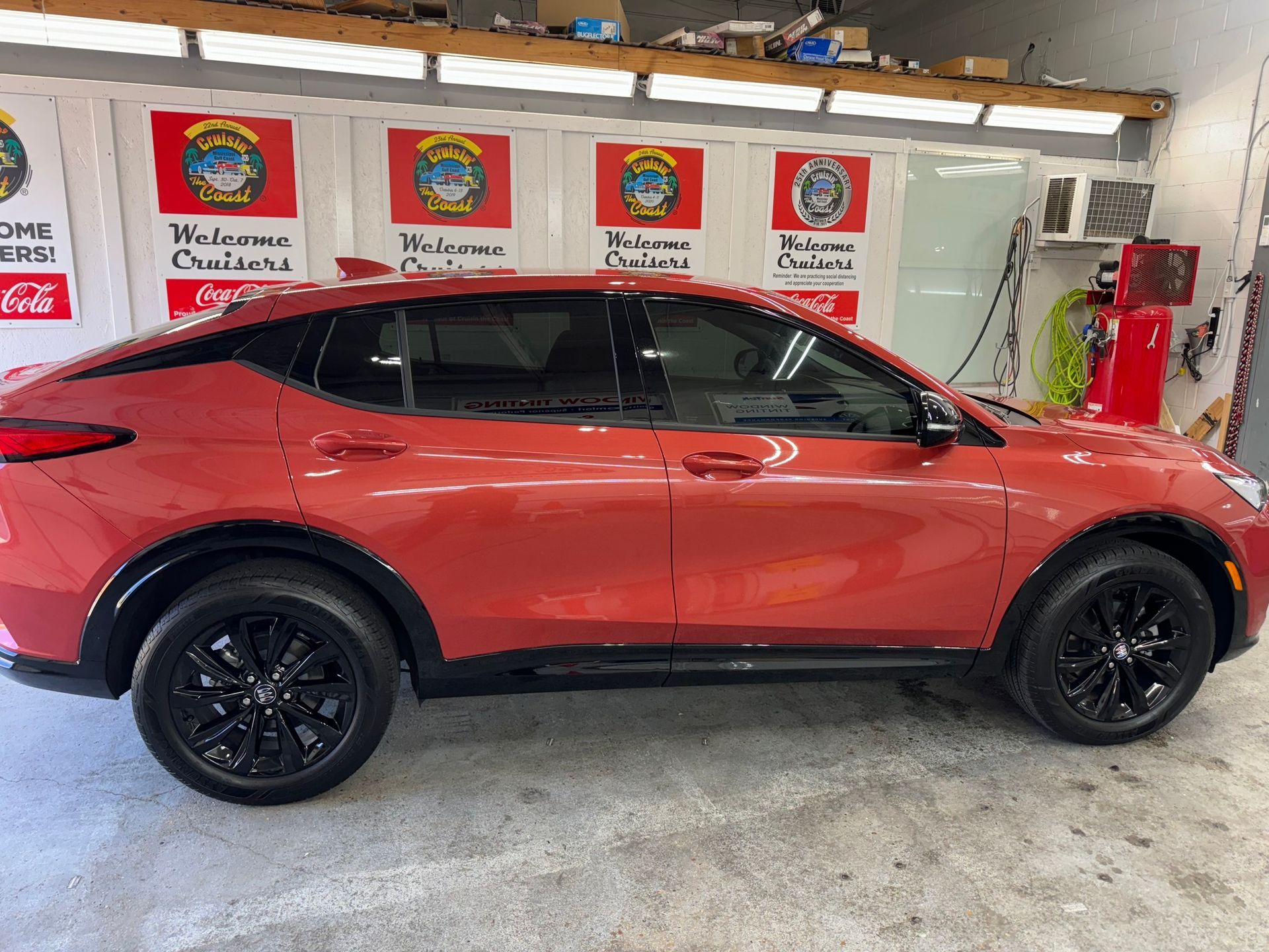 A red car with black wheels is parked in a garage.