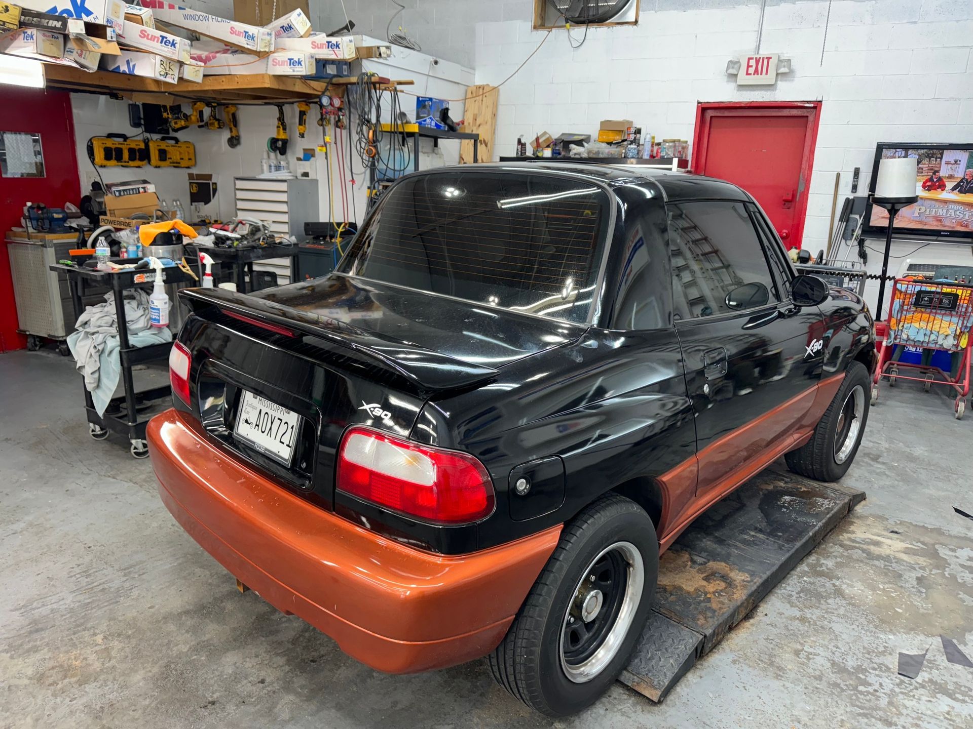 A black and orange car is parked in a garage.