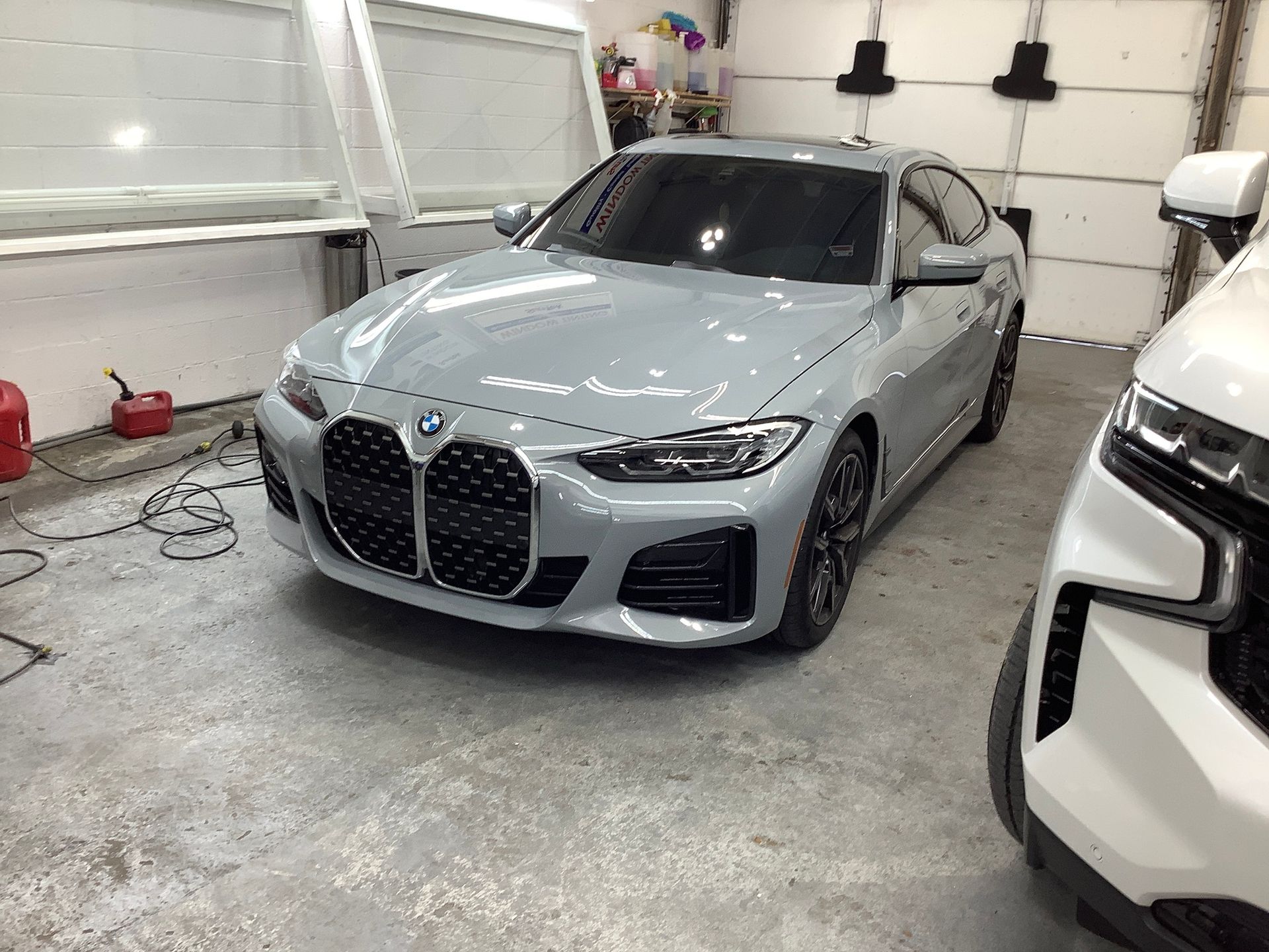 A bmw 4 series is parked in a garage next to a white suv.