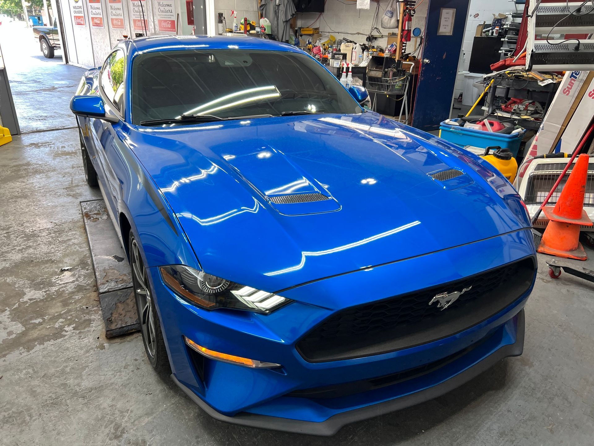 A blue ford mustang is parked in a garage.