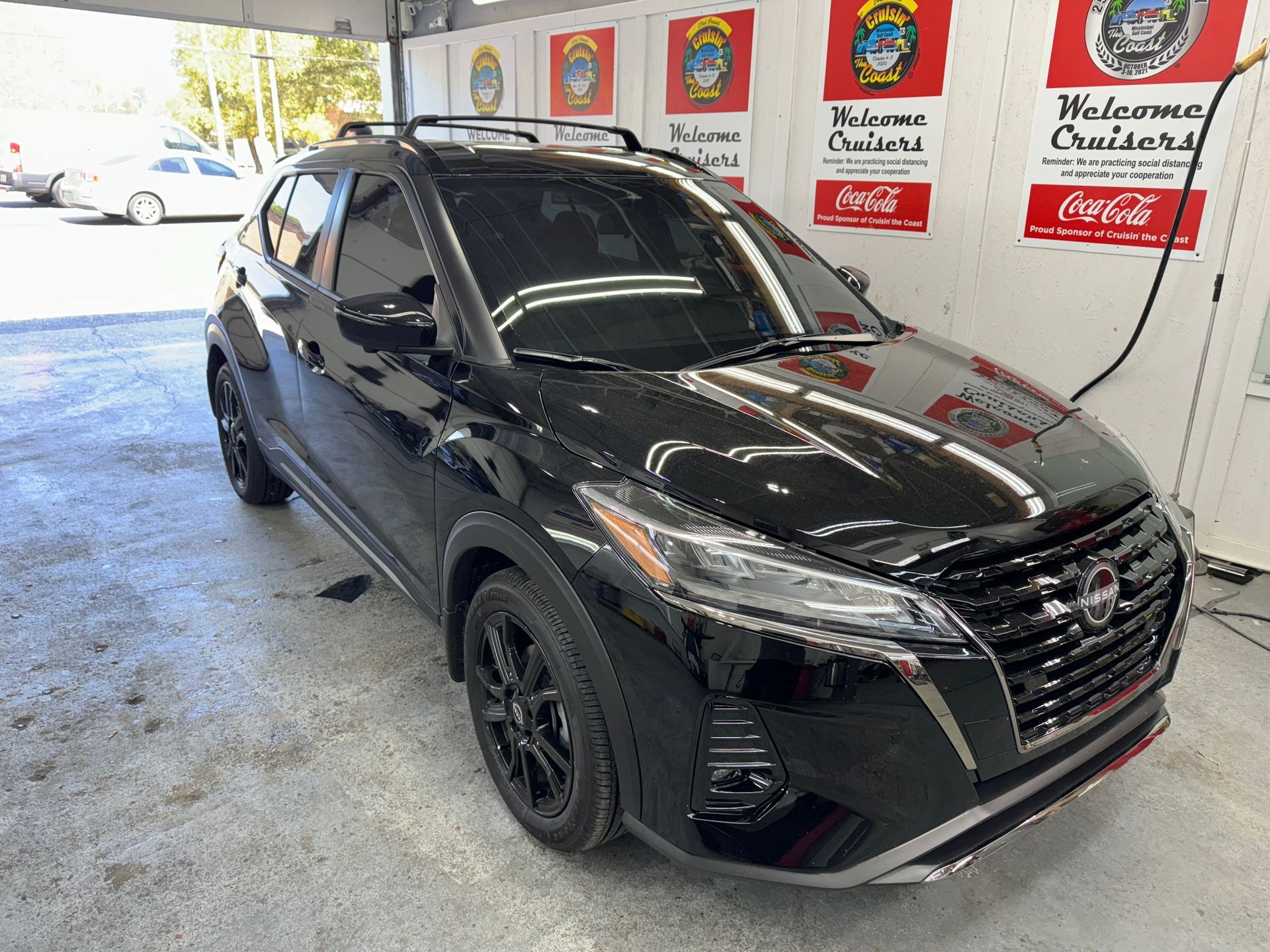 A black nissan kicks is parked in a car wash.