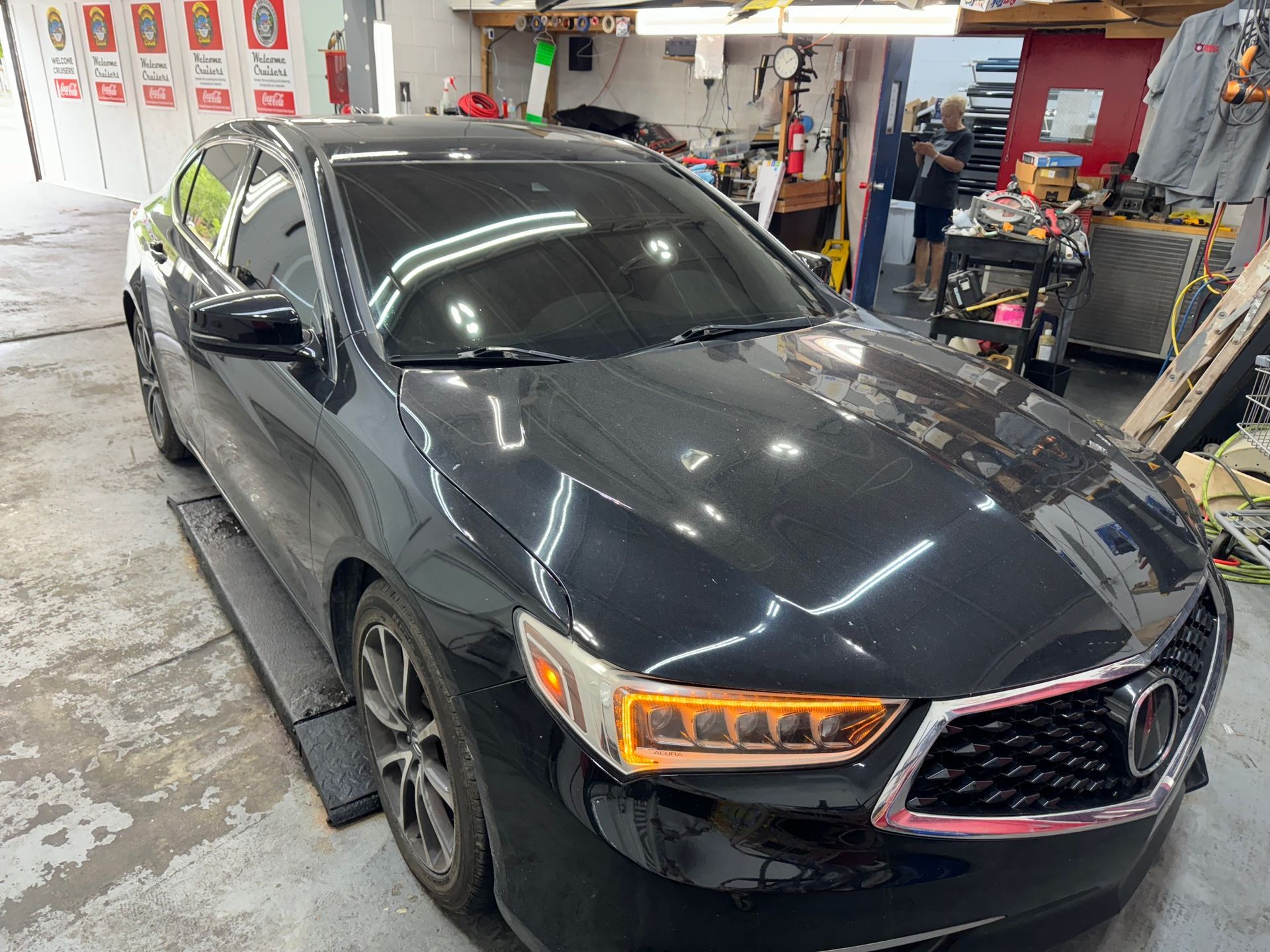 A black car is parked on a lift in a garage.