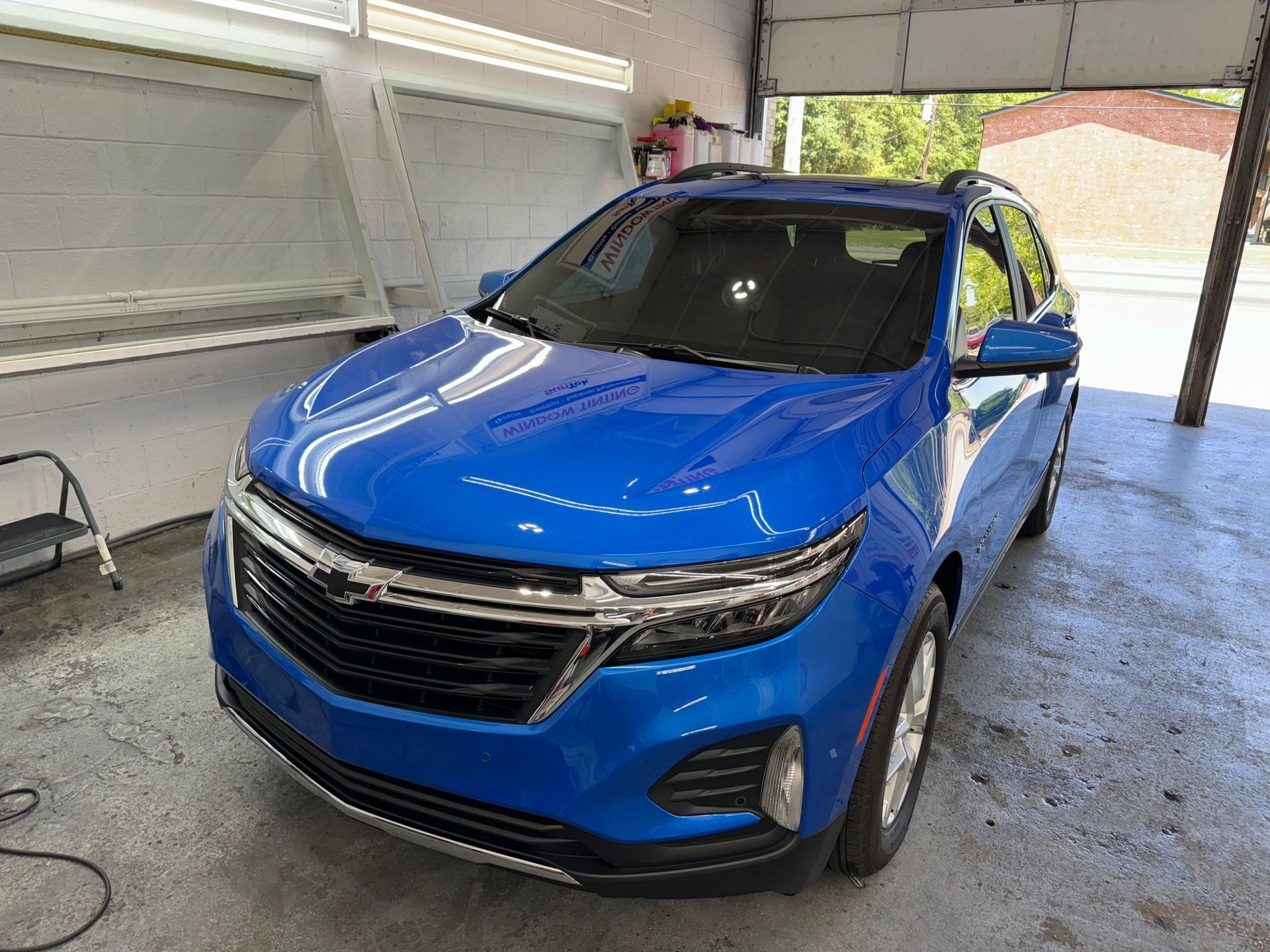 A blue car is parked in a garage next to a garage door.