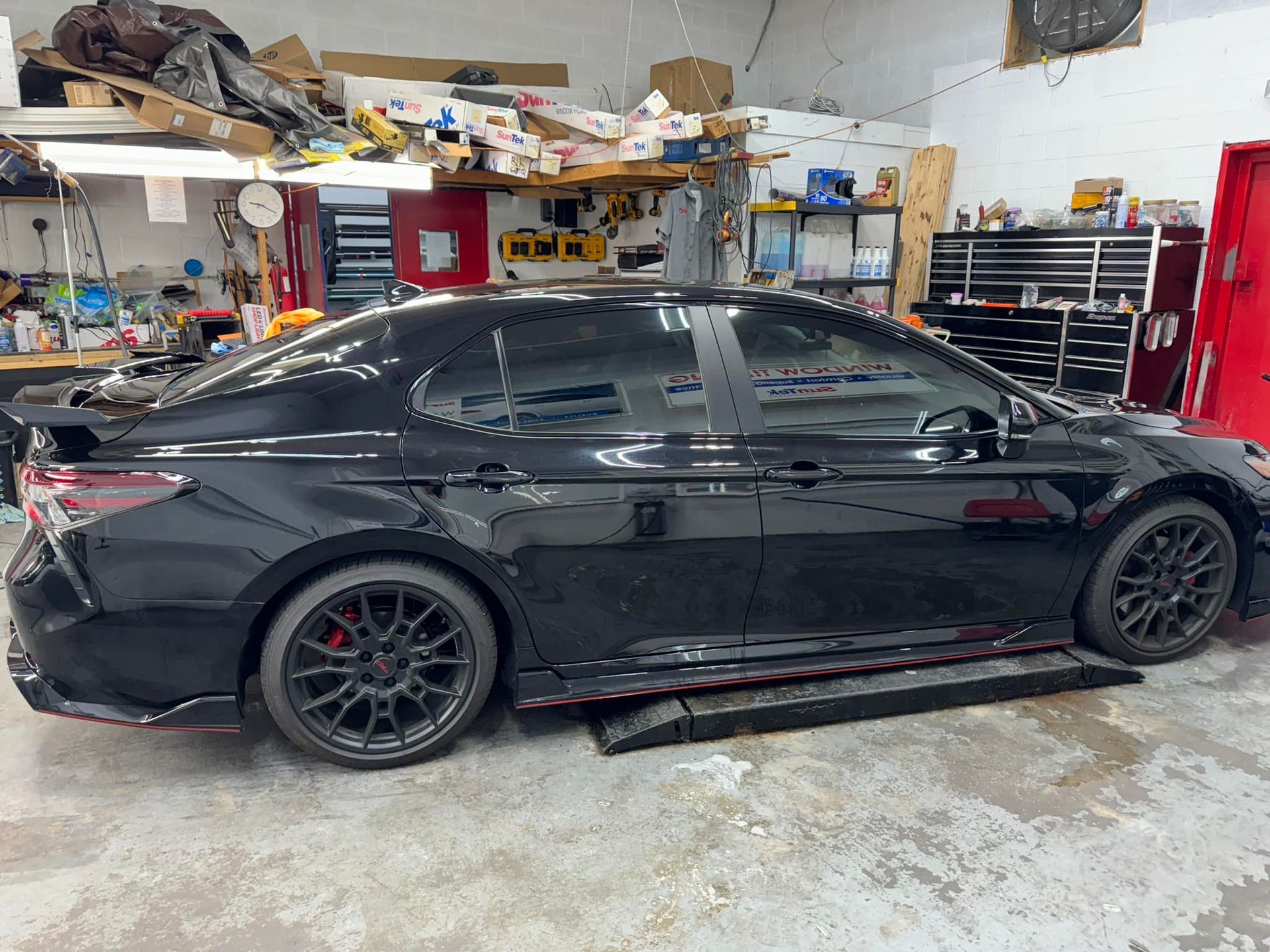 A black car is parked in a garage on a lift.