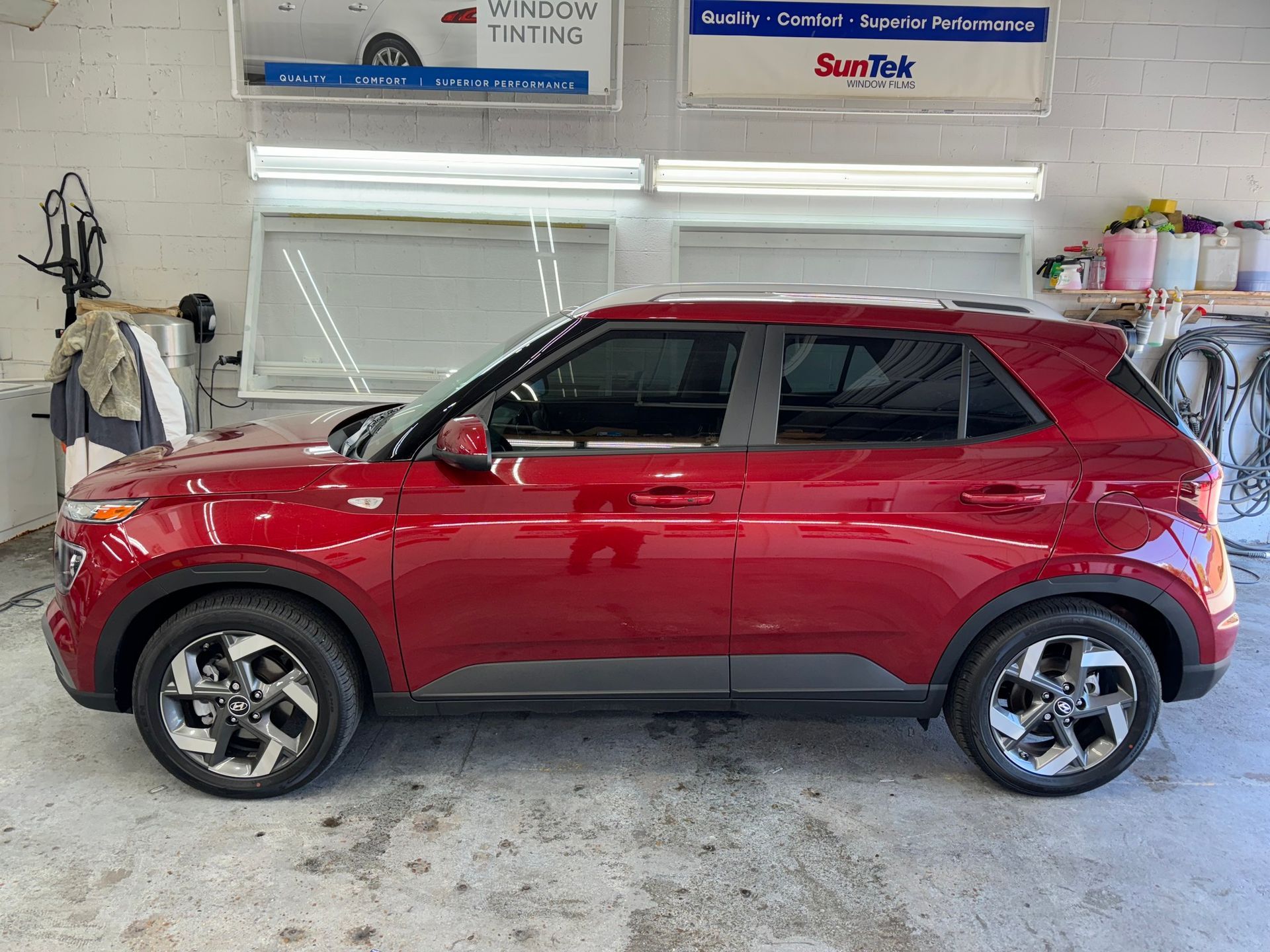 A red hyundai venue is parked in a garage.