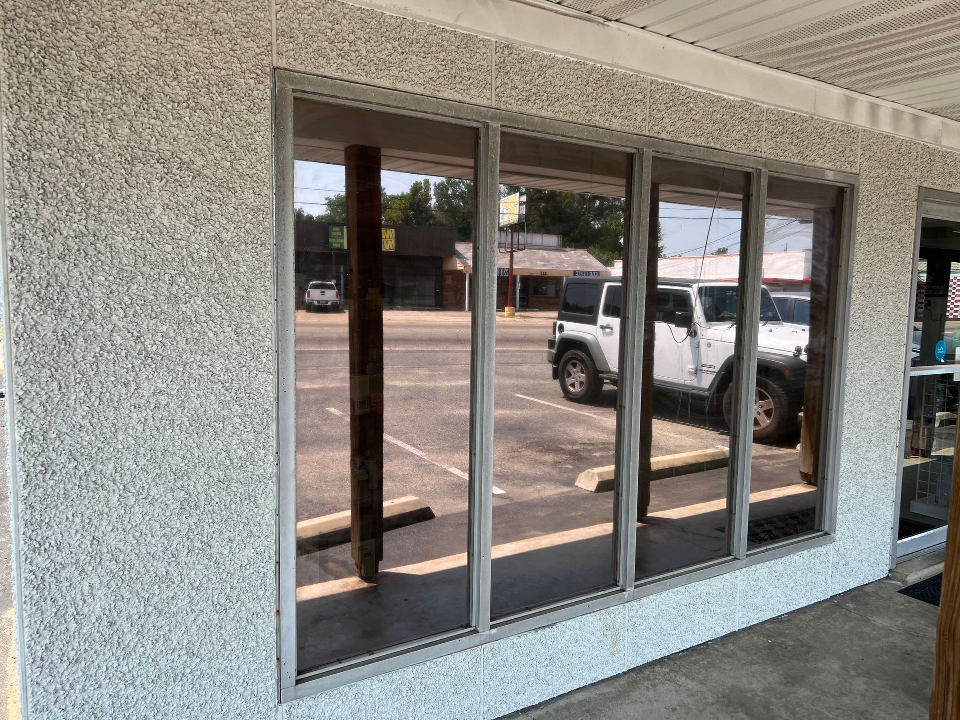A white jeep is parked in front of a building with a lot of windows.