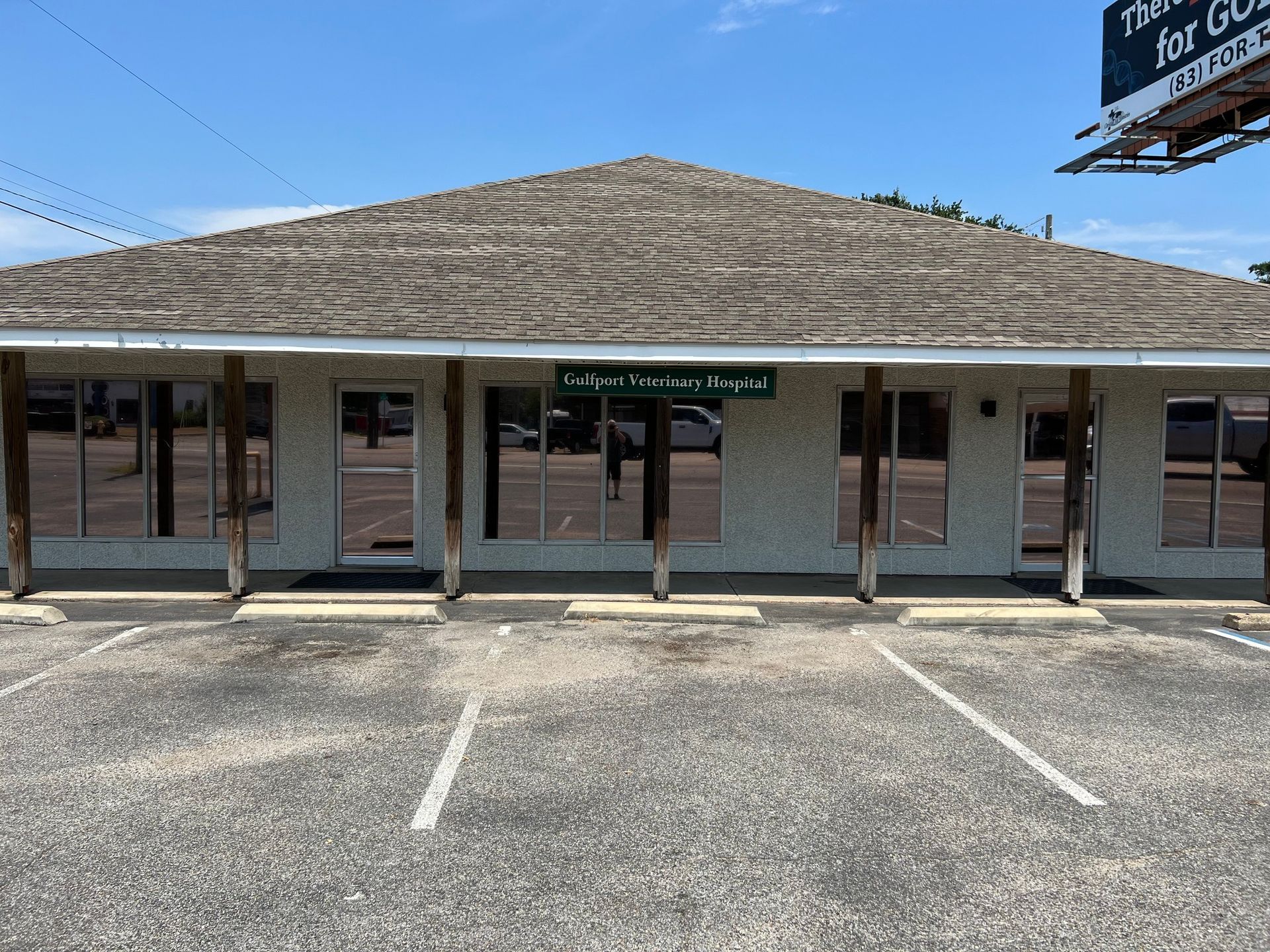 A white building with a thatched roof and a parking lot in front of it