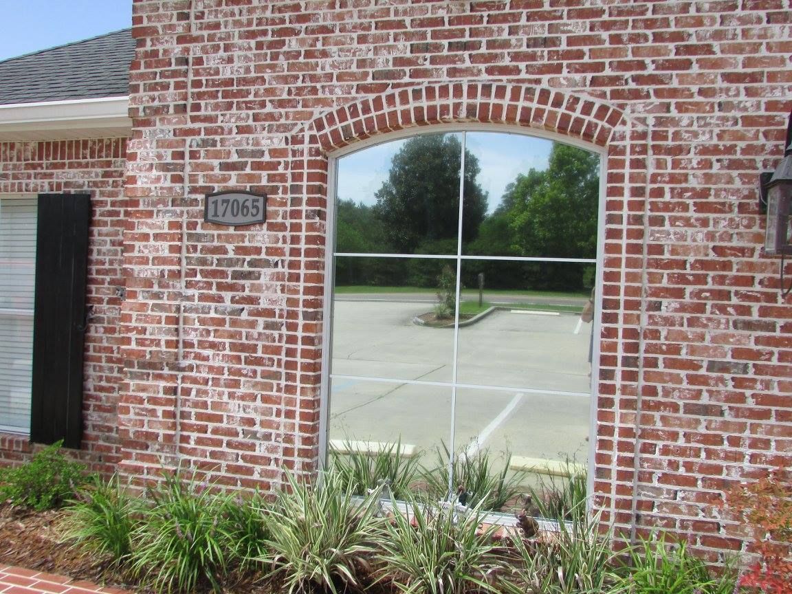 A brick building with a large window with a reflection of a parking lot