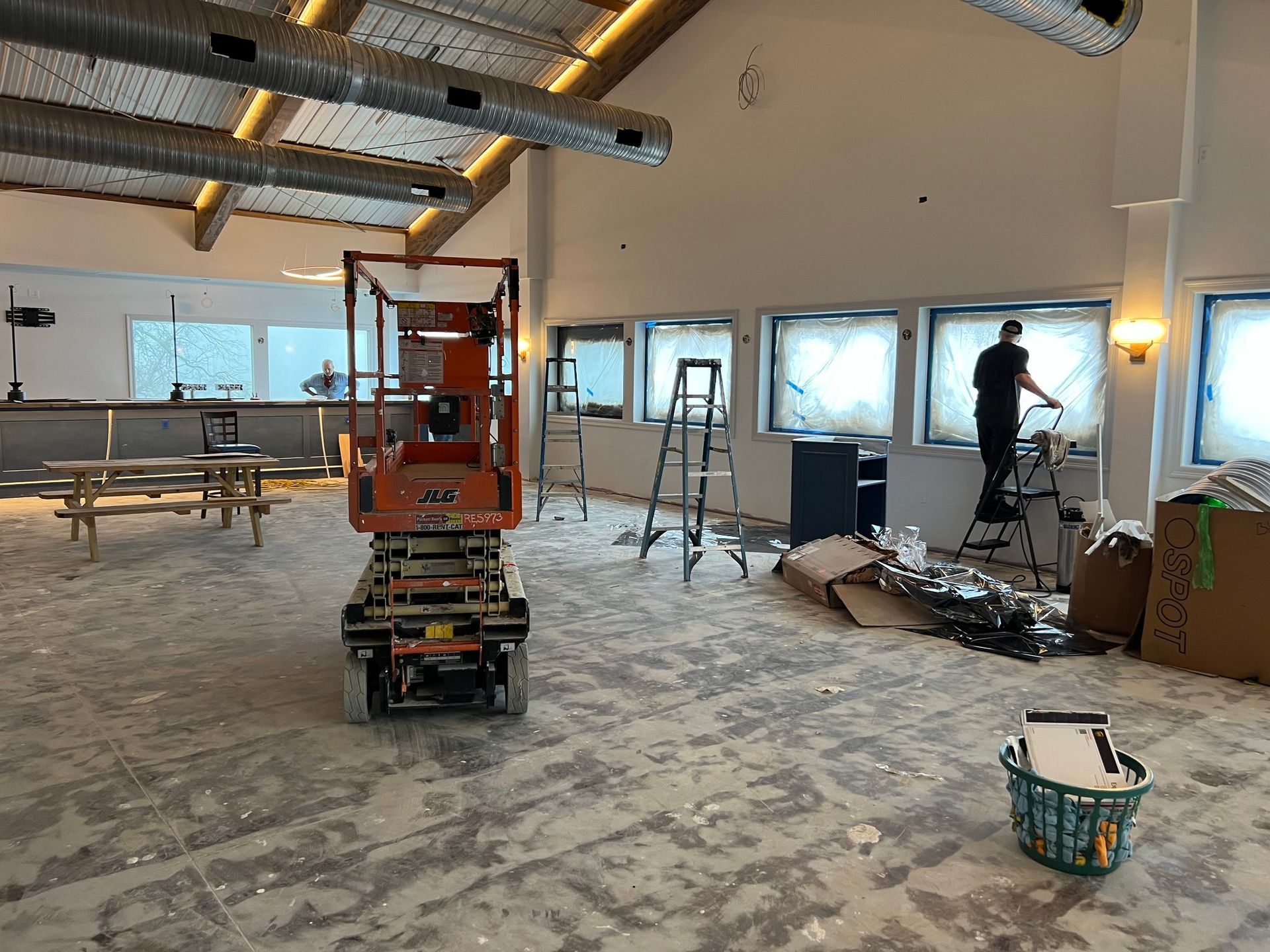 A man is standing on a ladder in an empty room.