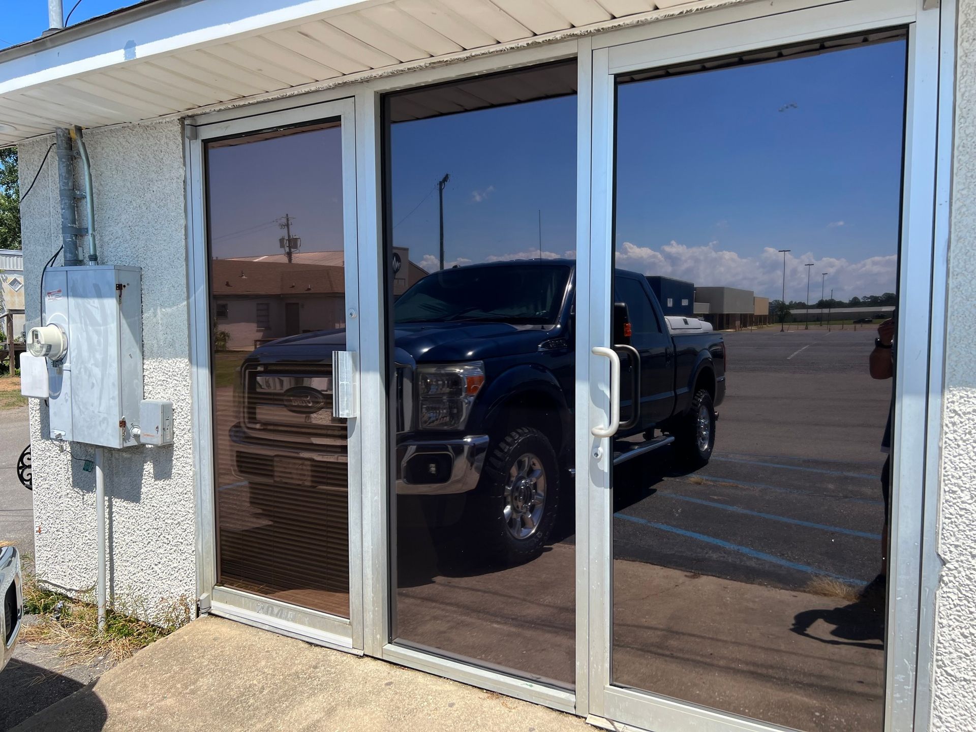 A truck is parked in front of a building with sliding glass doors.