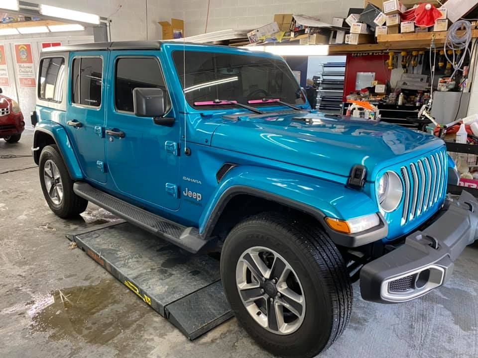 A blue jeep is parked on a lift in a garage.