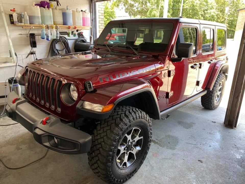A red jeep is parked in a garage.