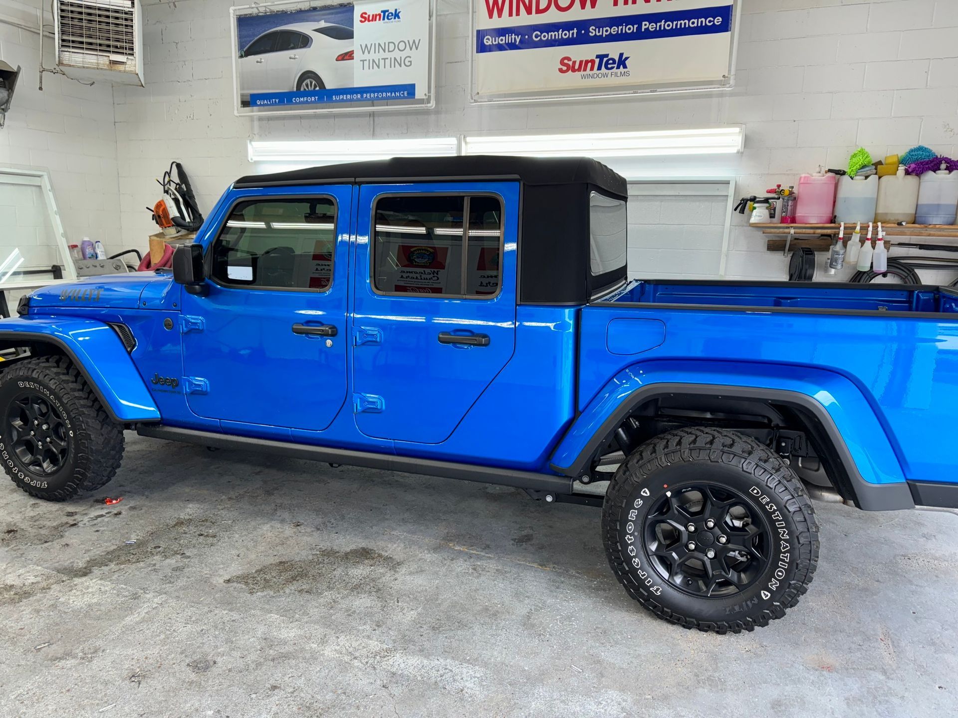 A blue jeep is parked in a garage.