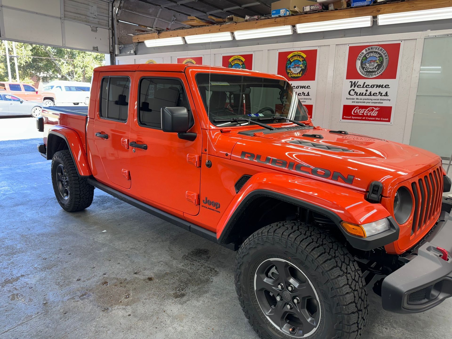 A red jeep gladiator pickup truck is parked in a garage.