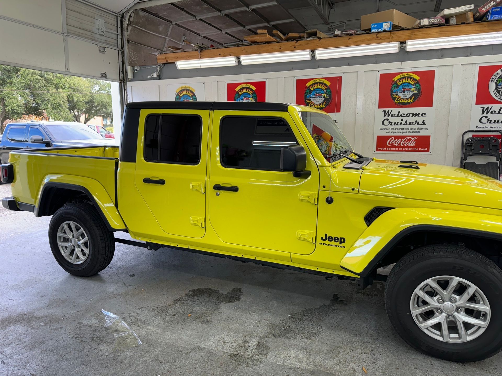 A yellow jeep gladiator pickup truck is parked in a garage.