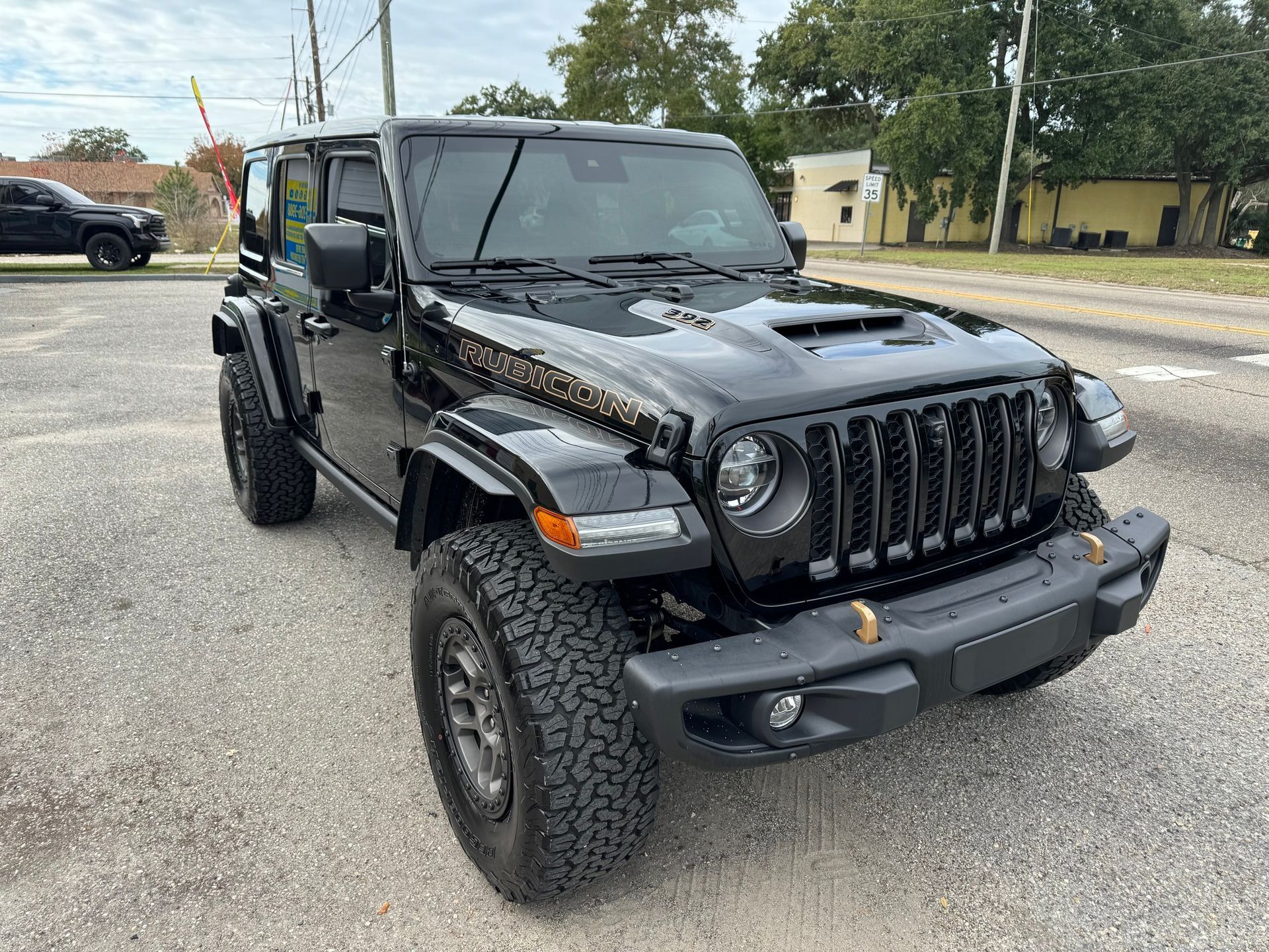 A black jeep wrangler is parked in a parking lot.