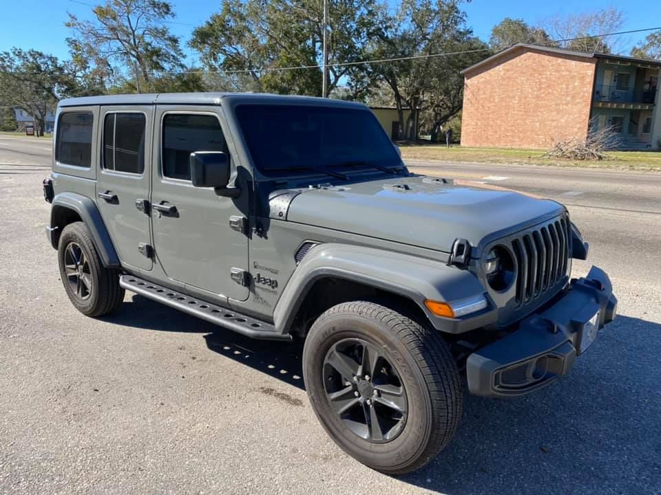 A gray jeep wrangler is parked on the side of the road.