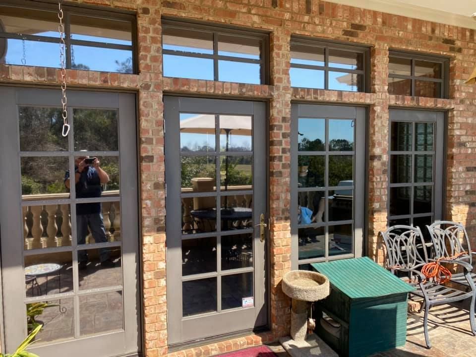 A man is taking a picture of a brick building with sliding glass doors.