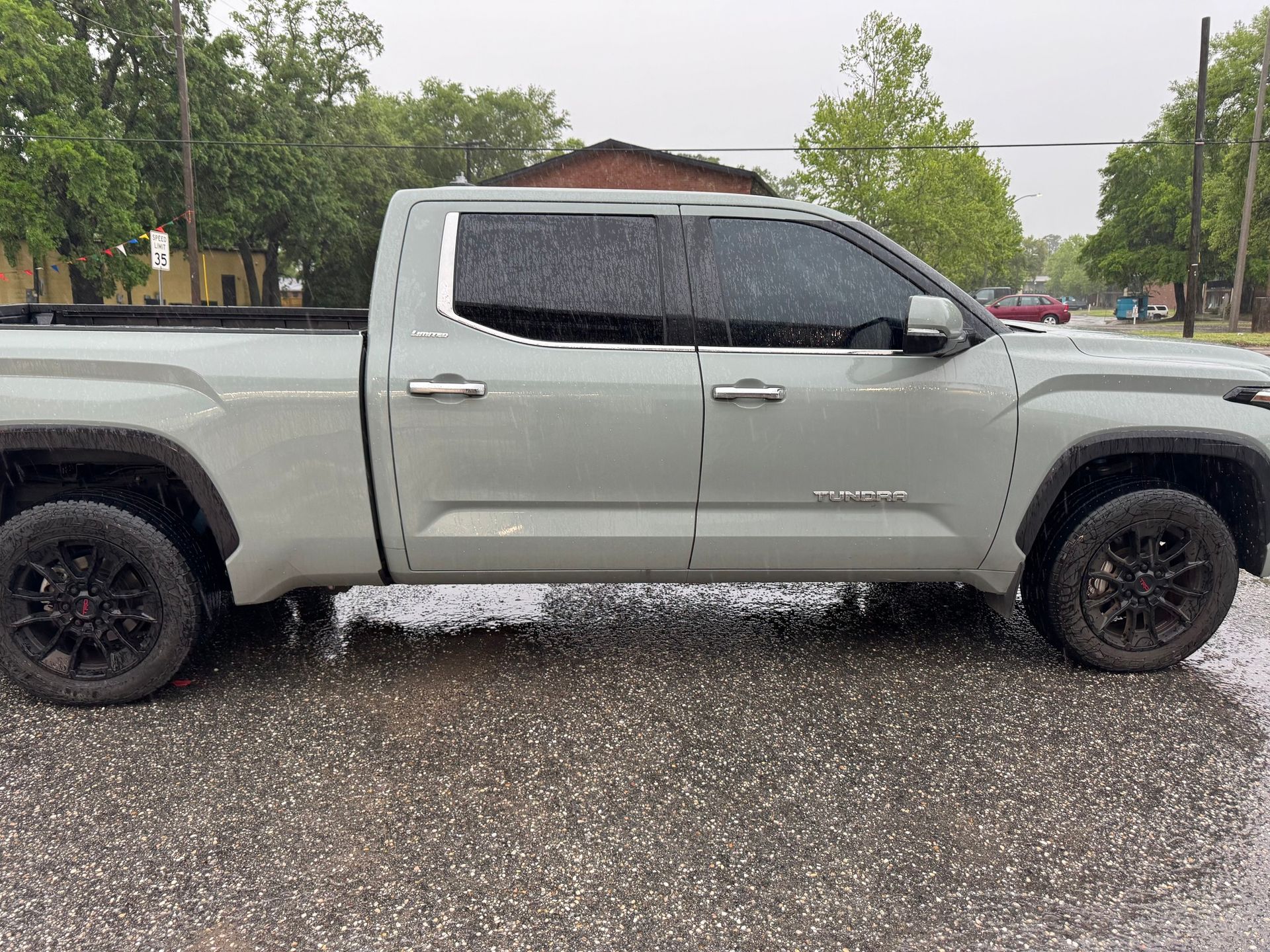 A gray truck is parked in a parking lot on a rainy day.