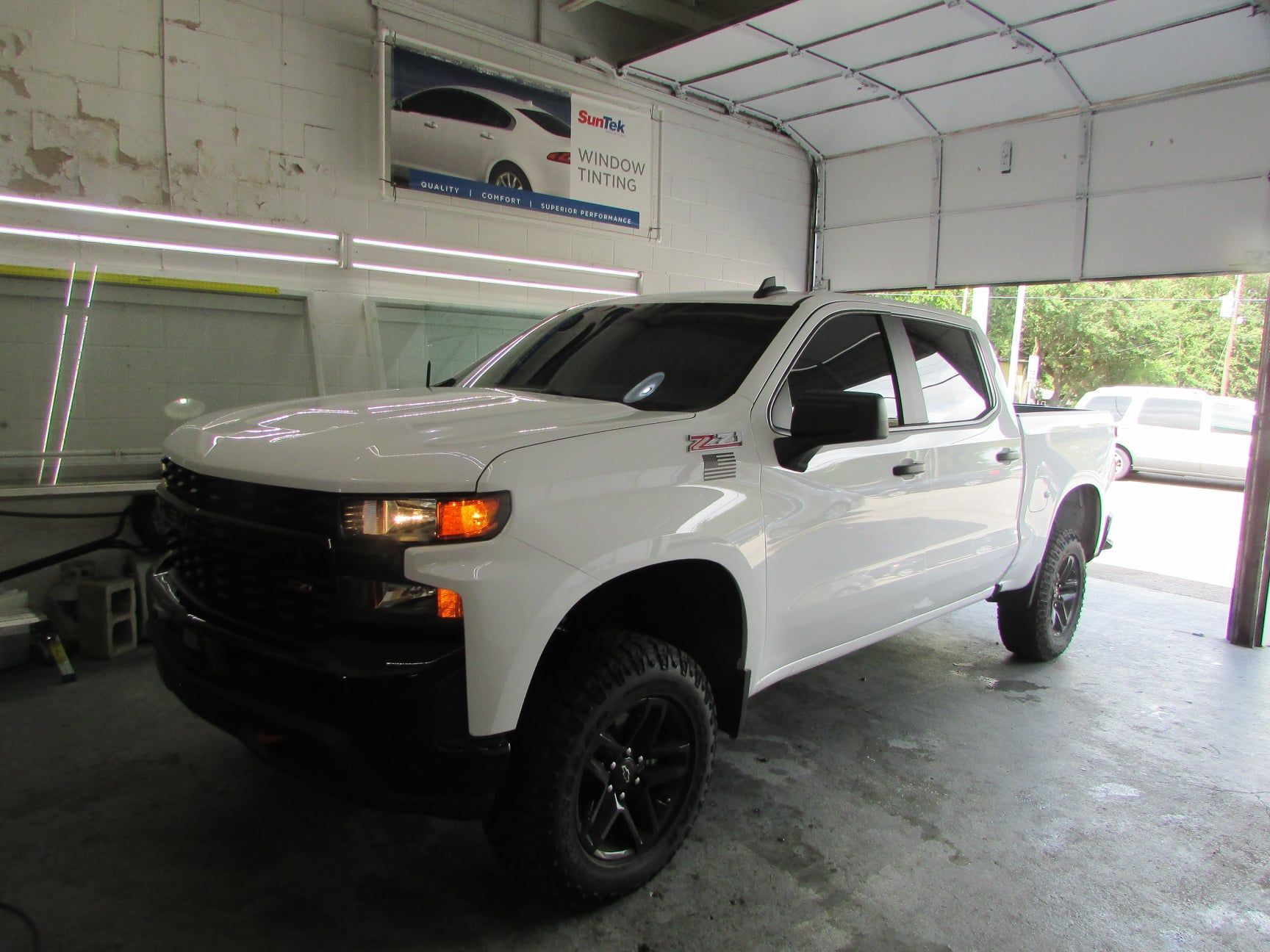 A white truck is parked in a garage.