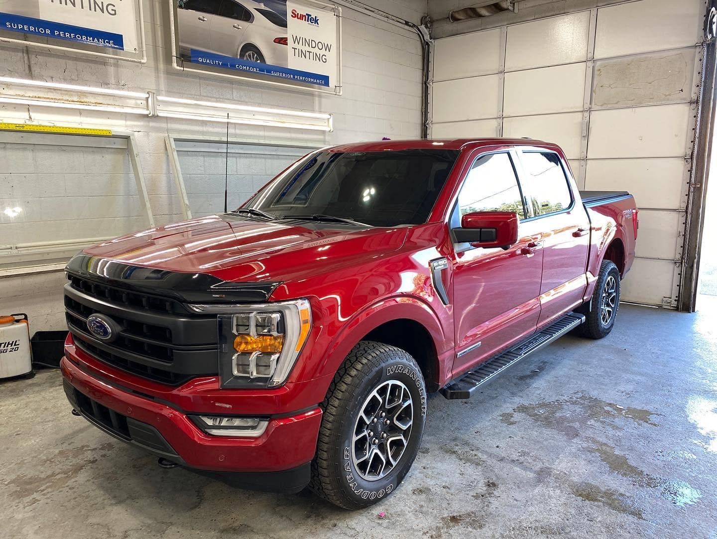 A red ford f150 truck is parked in a garage.